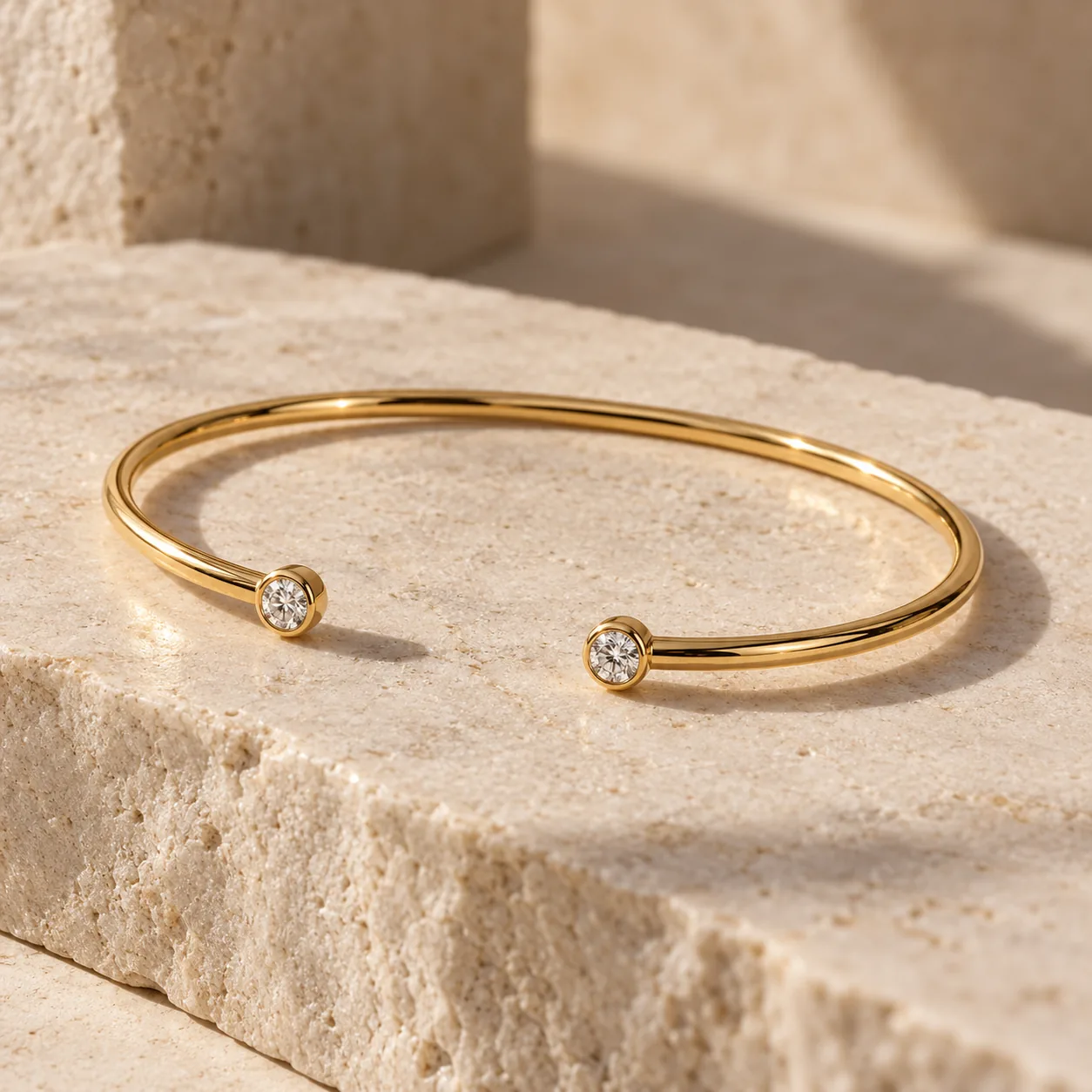 Open oval gold bangle tipped with two small white diamonds
