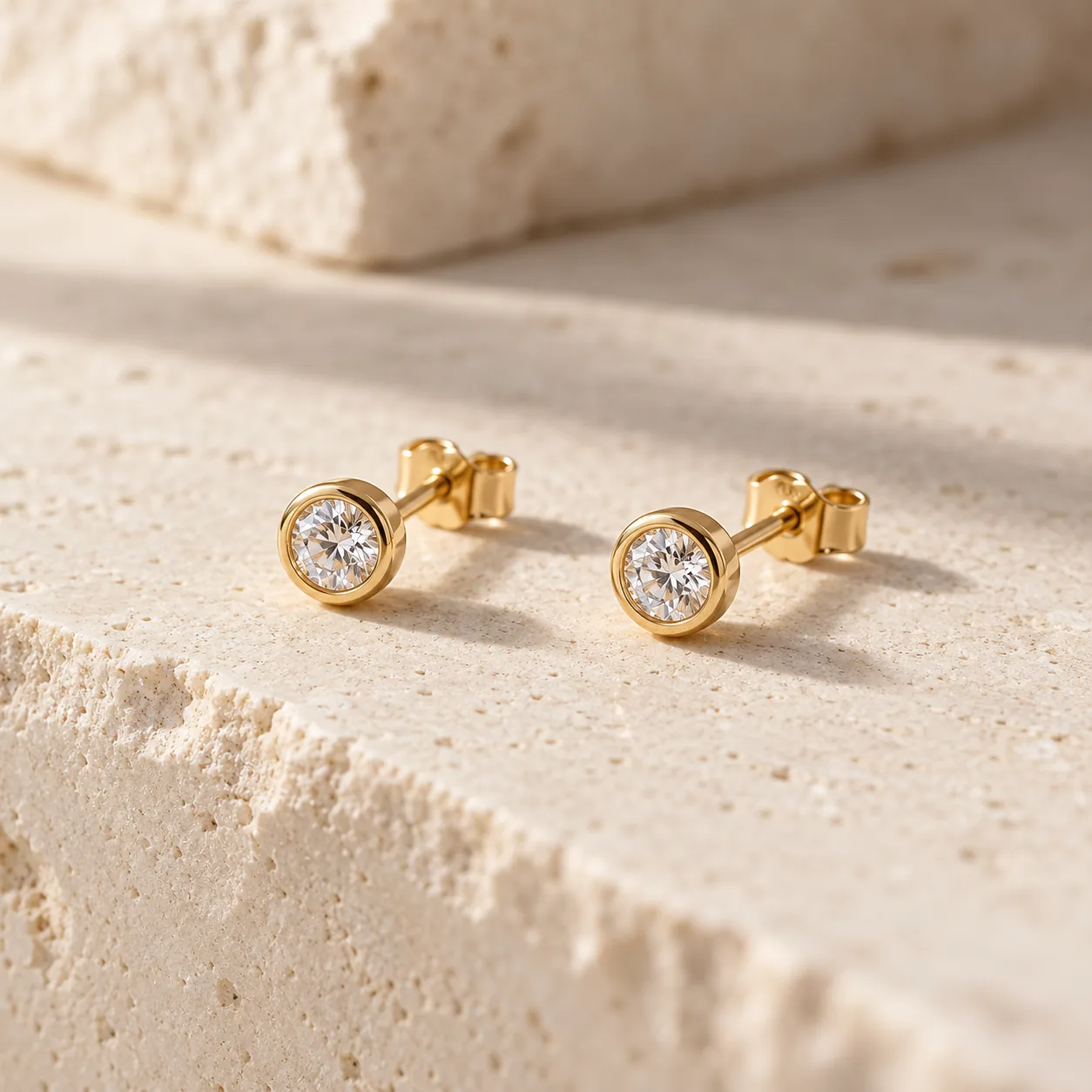 Pair of small round diamond studs in yellow gold bezel settings