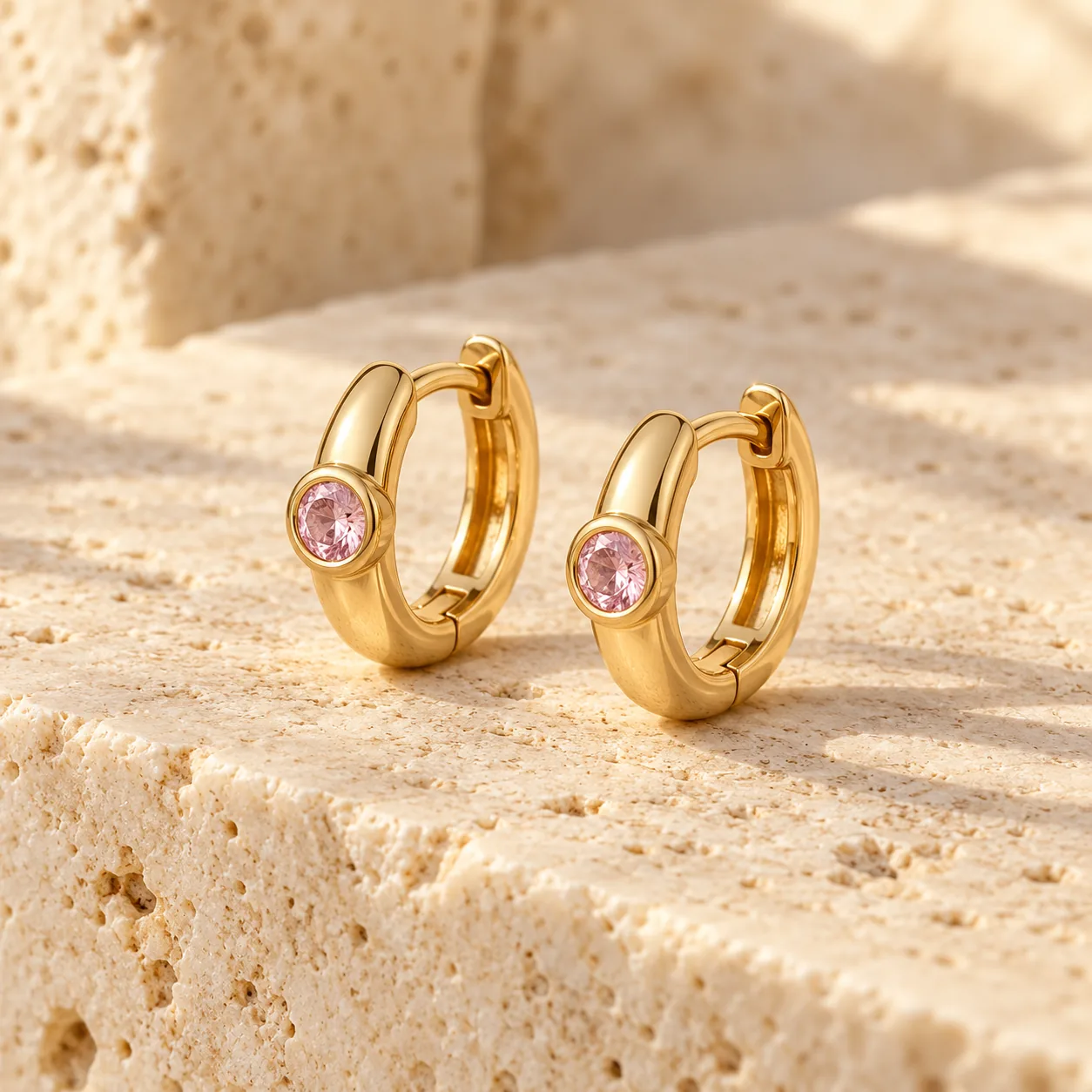 Small yellow gold huggie hoops with round blush pink sapphires